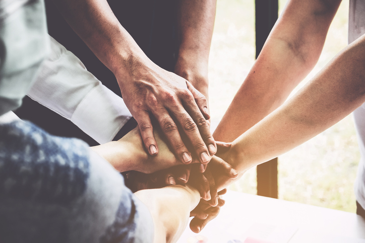 Group of business people putting their hands working together on wooden background in office. group support teamwork agreement concept.