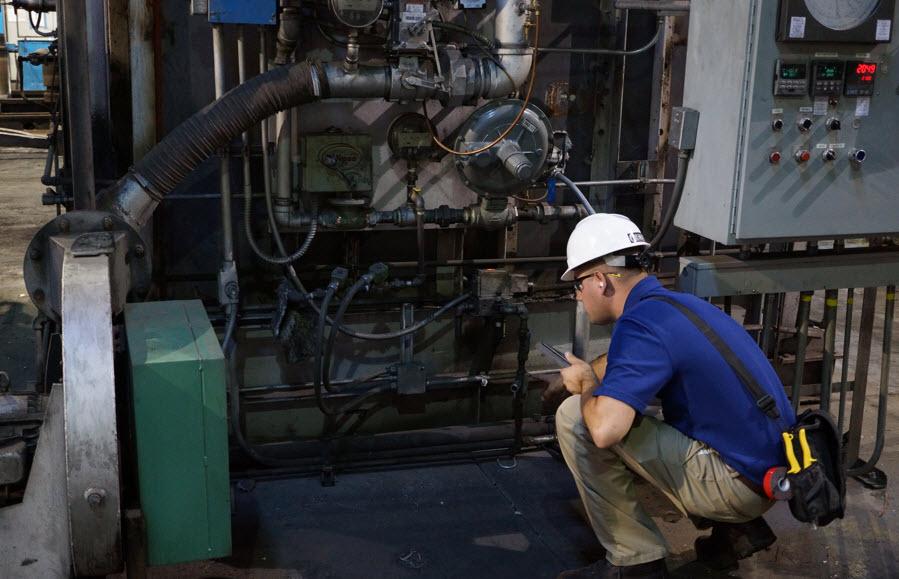 Man in hard hat inspecting machine