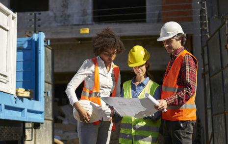 Workers looking at plan with hardhats on.